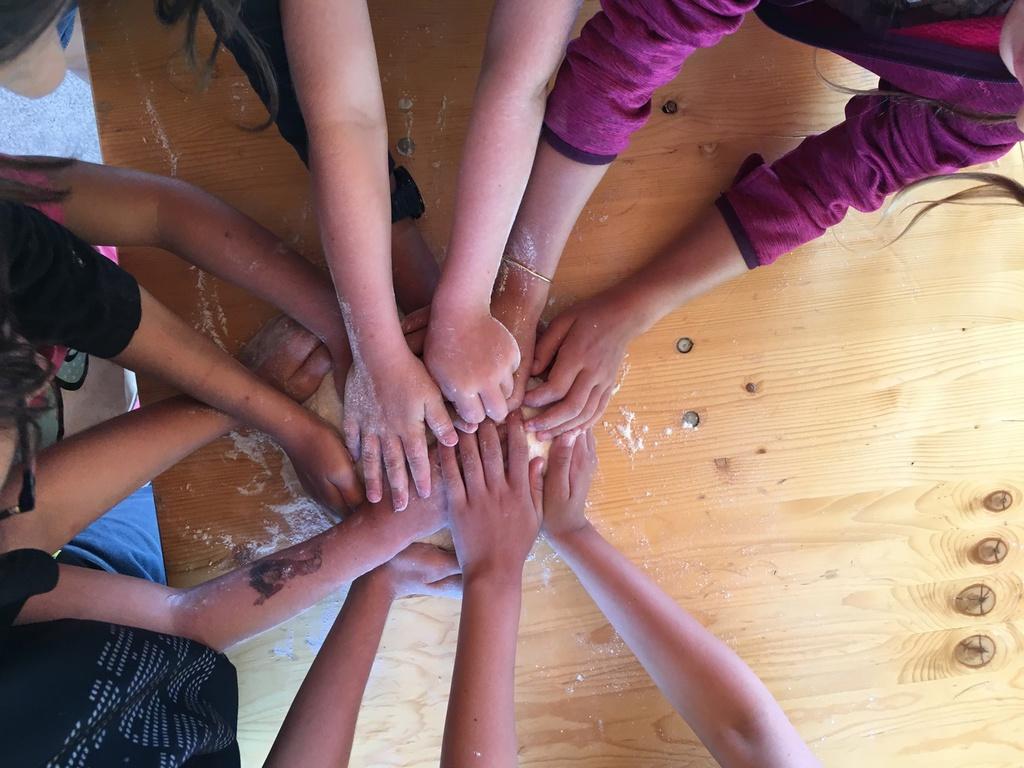 Photo de bras d'enfants sur un pâton pendant un atelier de fabrication du pain